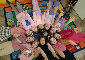 Dziewczynki z klasy trzeciej B pozują leżąc na dywanie tworząc koło