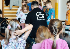 Dzieci z pracownikiem fundacji FAR sprawdzają perspektywę osób poruszających się na wózku