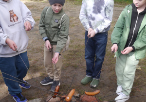 Uczniowie pieką kiełbaski przy ognisku